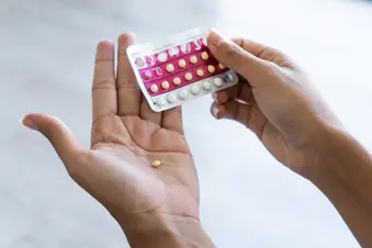 photo of woman holding birth control pills