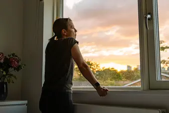 photo of woman looking out of window at sunset