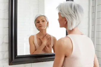photo of older woman looking in mirror