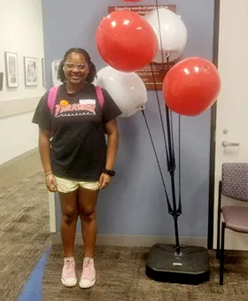 photo of girl standing next to balloons