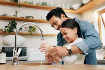 photo of father helping daughter wash hands