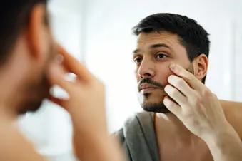 photo of man applying moisturizer to face