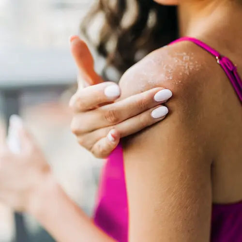 photo of woman applying lotion to shoulder