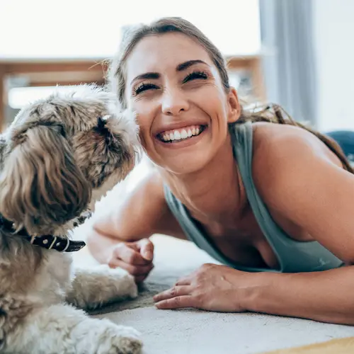 photo of woman playing with her dog at home