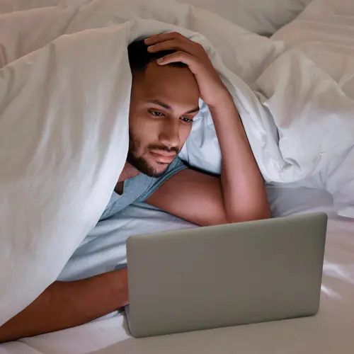 photo of man using laptop in bed