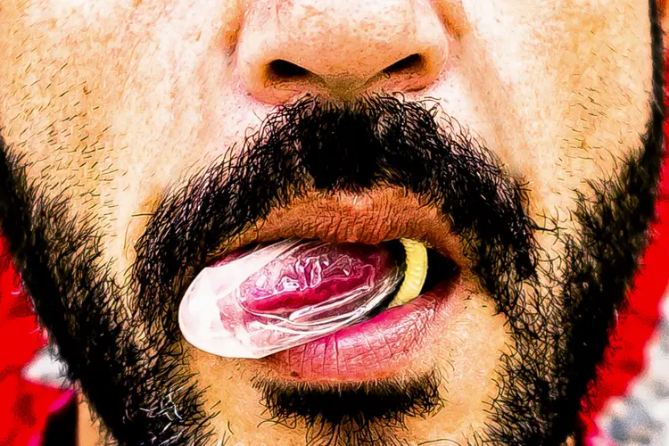 photo of male with a condom on his tongue