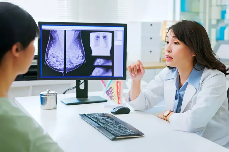 Photo of doctor-patient consultation, where an Asian female doctor explains mammography results to female patient