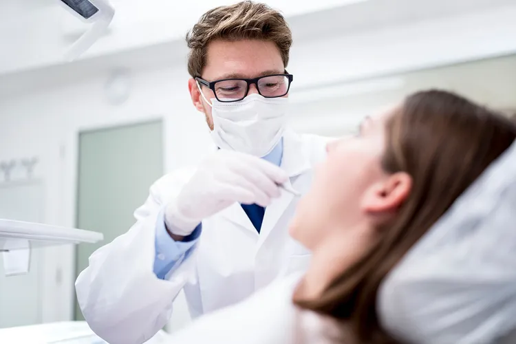 photo of dentist examining patient