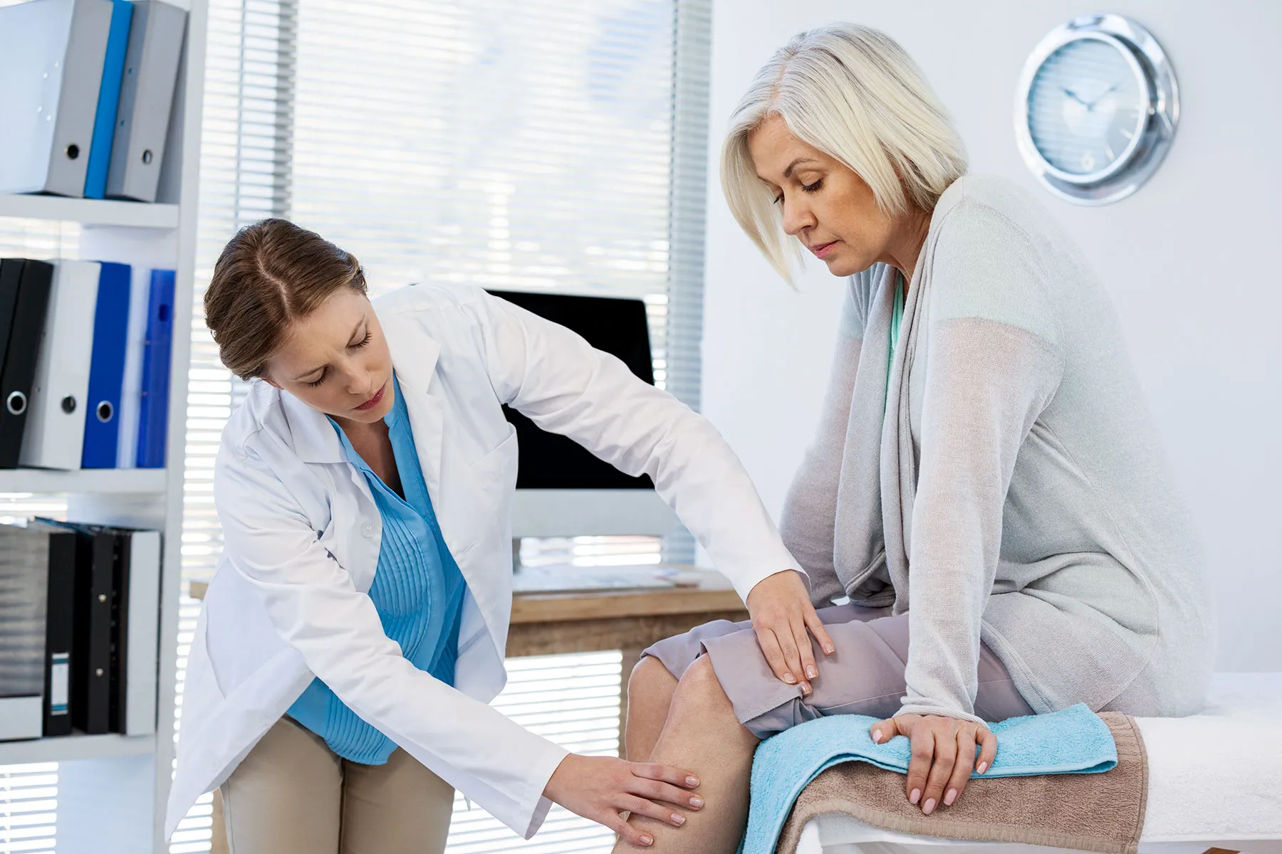 photo of doctor examining patient knee in clinic