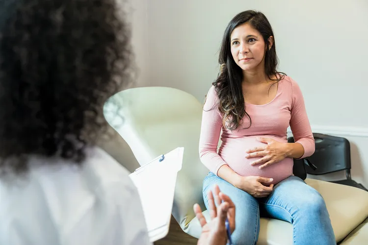 photo of pregnant woman talking with doctor