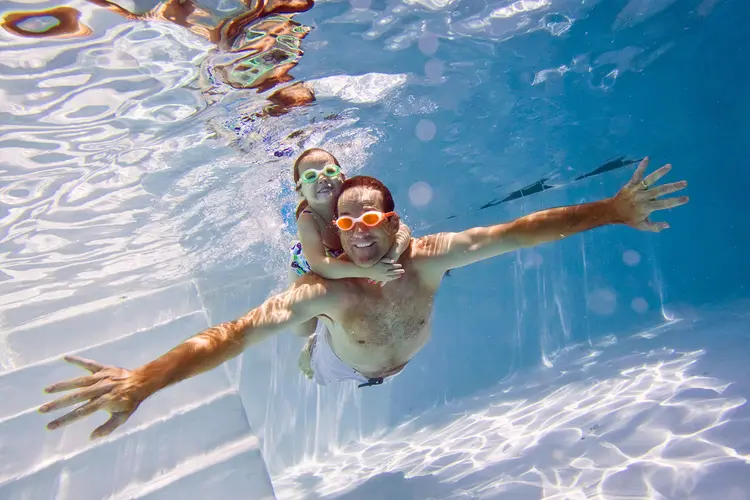 photo of father and daughter swimming in pool