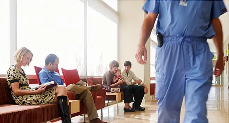 People in waiting area of hospital with surgeon