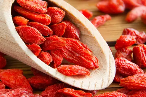 photo of dried goji berries and wooden spoon