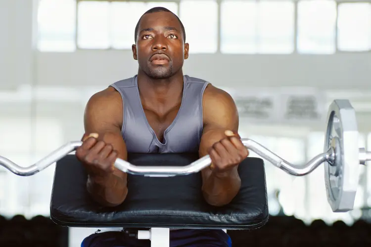photo of man curling weights in gym