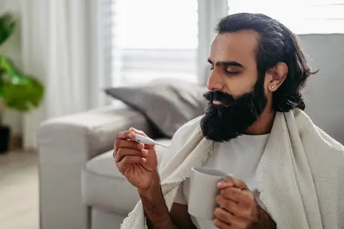 photo of man taking temperature at home