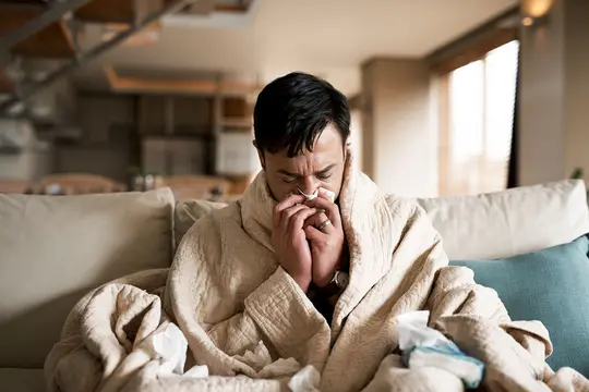 photo of man blowing nose on couch