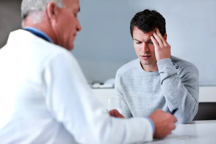 photo of man with headache talking with doctor