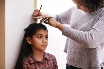 photo of mother measuring daughter's height