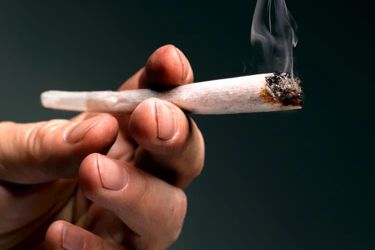 photo of hand holding marijuana cigarette