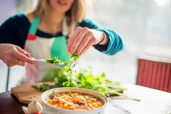 photo of woman seasoning soup