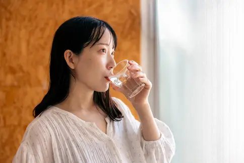 photo of young woman drinking glass of water
