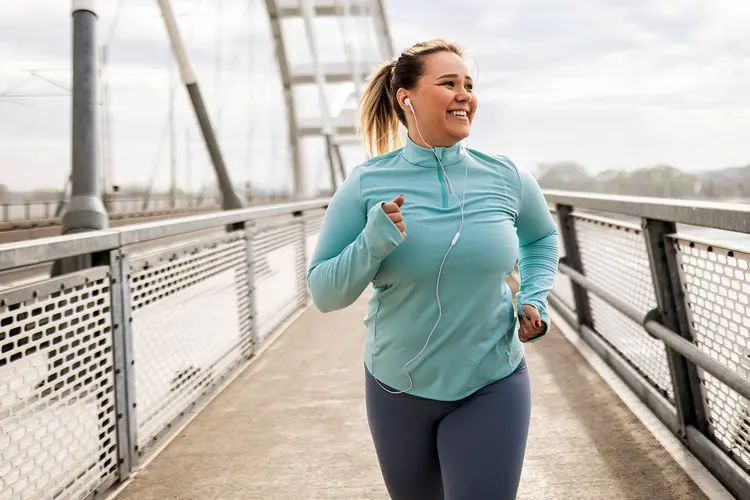 photo of young woman jogging on bridge which helps you stay active, keep lower blood sugar levels, and A1c