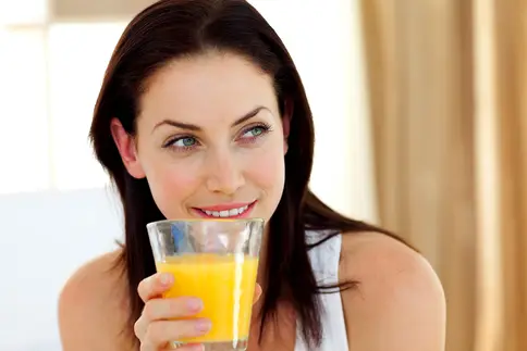 photo of woman drinking glass of orange juice
