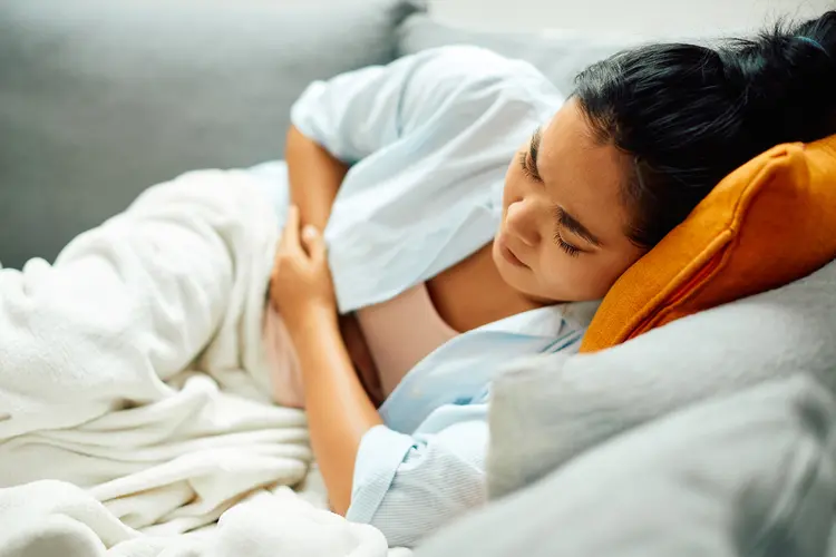 photo of woman on sofa with stomach cramps