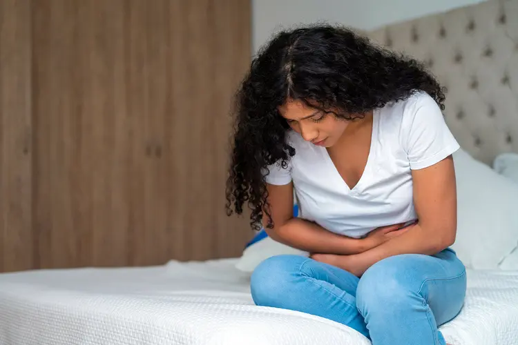 photo of young woman with stomach pain on bed