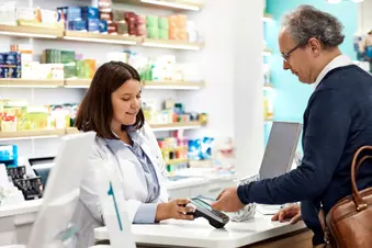 photo of mature man paying at pharmacy counter