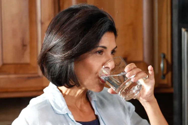 photo of woman drinking glass of water in kitchen