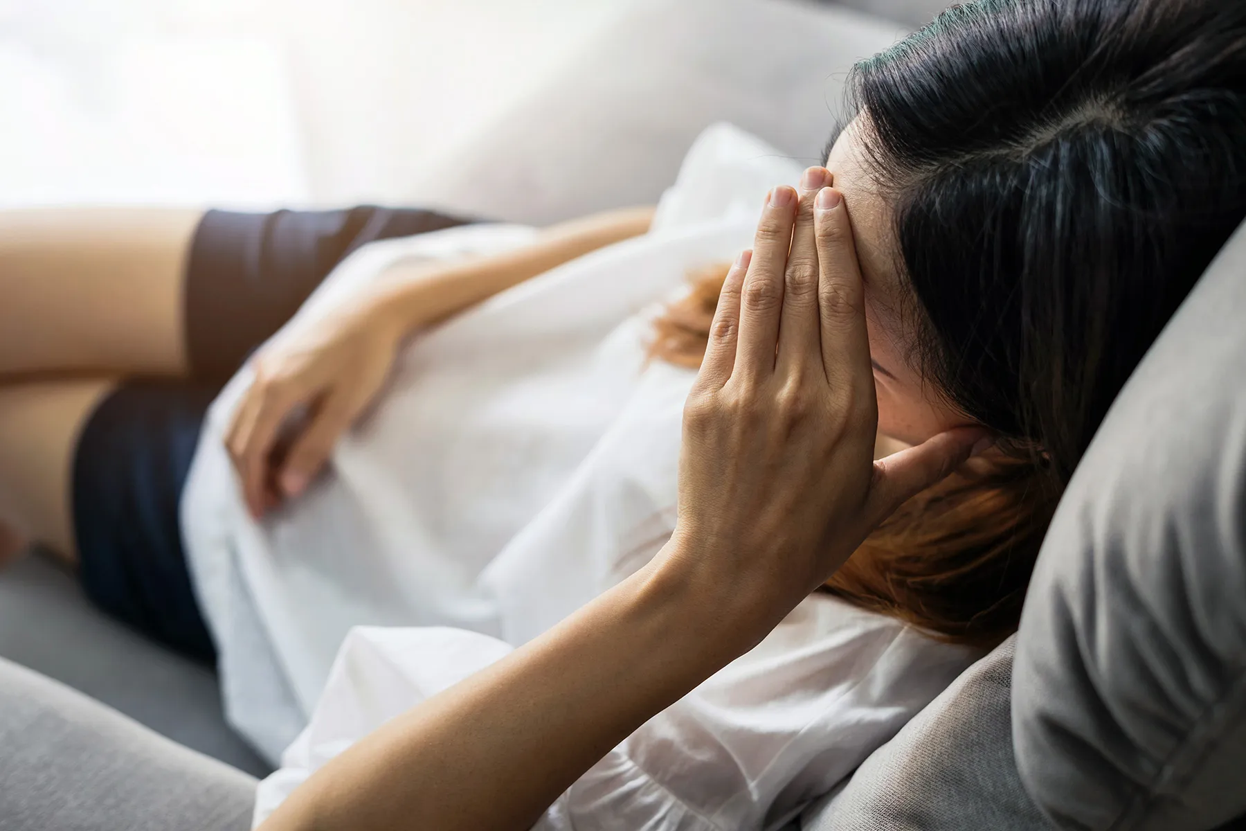 photo of depressed, young woman on sofa