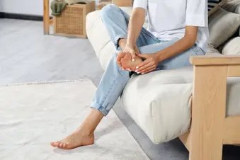 photo of woman rubbing sore foot at home