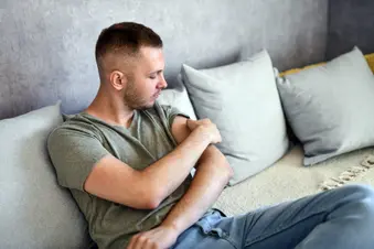 photo of young man scratching upper arm