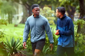 photo of male friends talking while walking in park