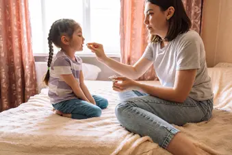 photo of mother giving her young daughter a pill