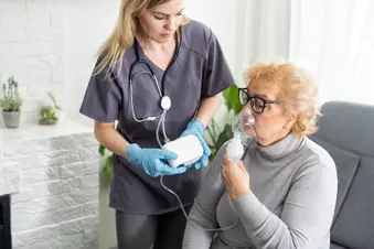 photo of nurse helping senior patient with nebulizer at home