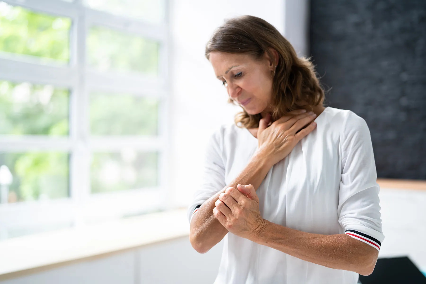 photo of mature woman scratching her arm
