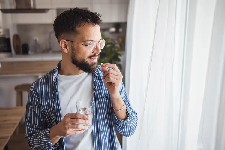photo of young man taking pill
