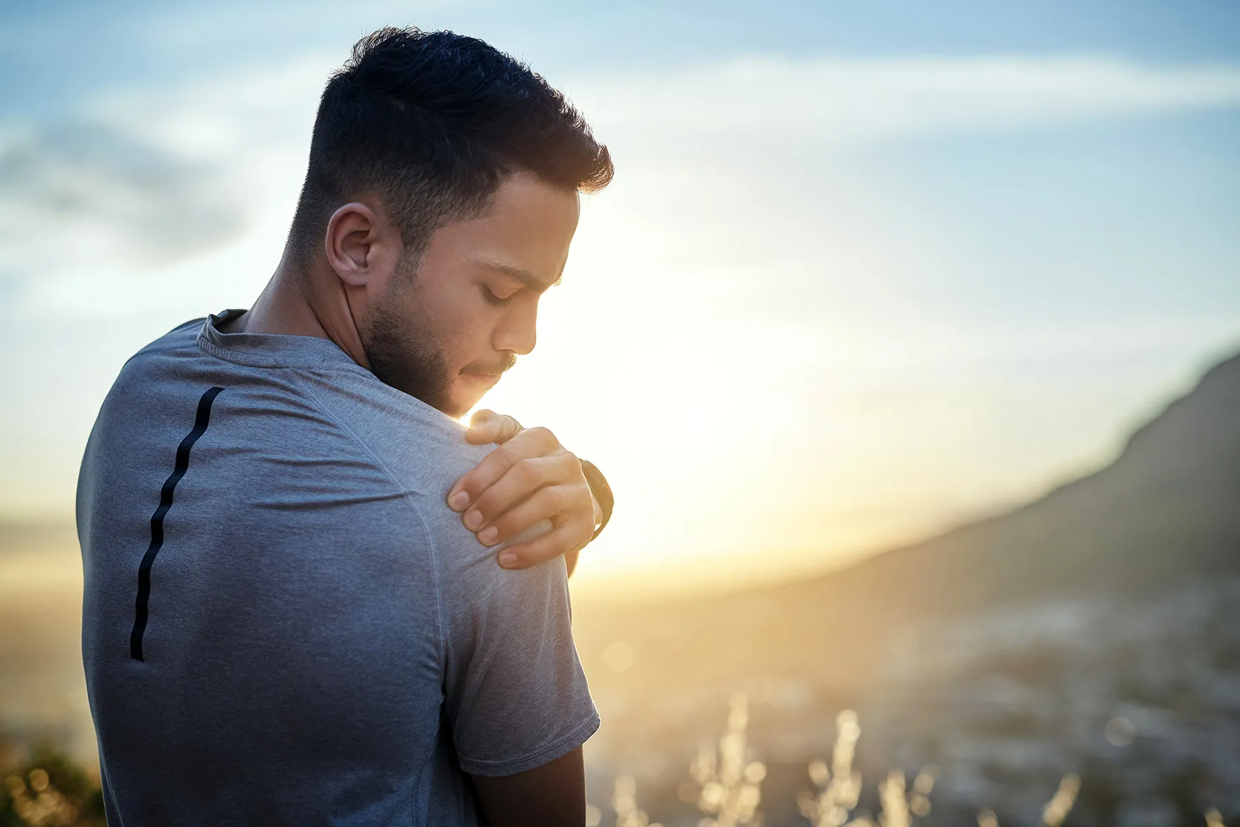 photo of young man holding sore shoulder