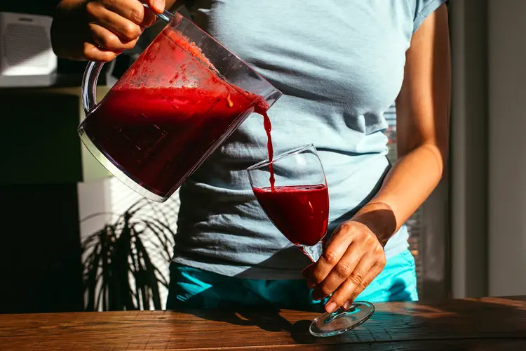 Photo of woman pouring fresh-squeezed juice into glass for a sleepy girl mocktail