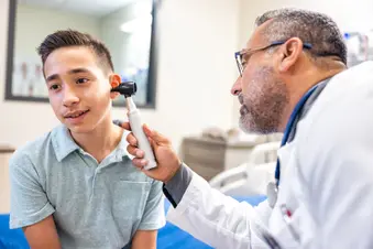 photo of doctor examining ear of teenage boy