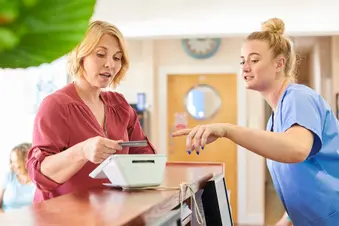 photo of female patient chats with medical receptionist while making payment