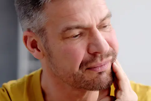 photo of mature man rubbing sore jaw