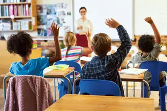 photo of children raising hands in classroom