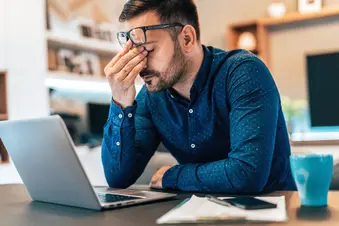 photo of tired young man working on laptop