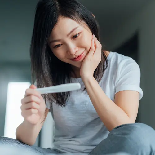 photo of happy woman looking at pregnancy test