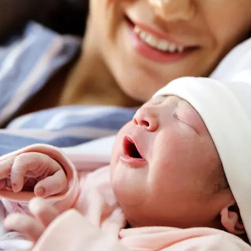 photo of smiling mother with newborn baby