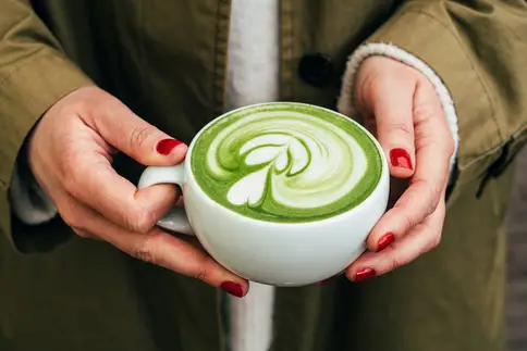 photo of hands holding a cup of matcha latte