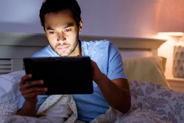 Blue light is known to interfere with your sleep cycle. Consider limiting screen time immediately before bed or adjusting your device to a dimmer setting. (Photo Credit: Tetra images/Getty Images)